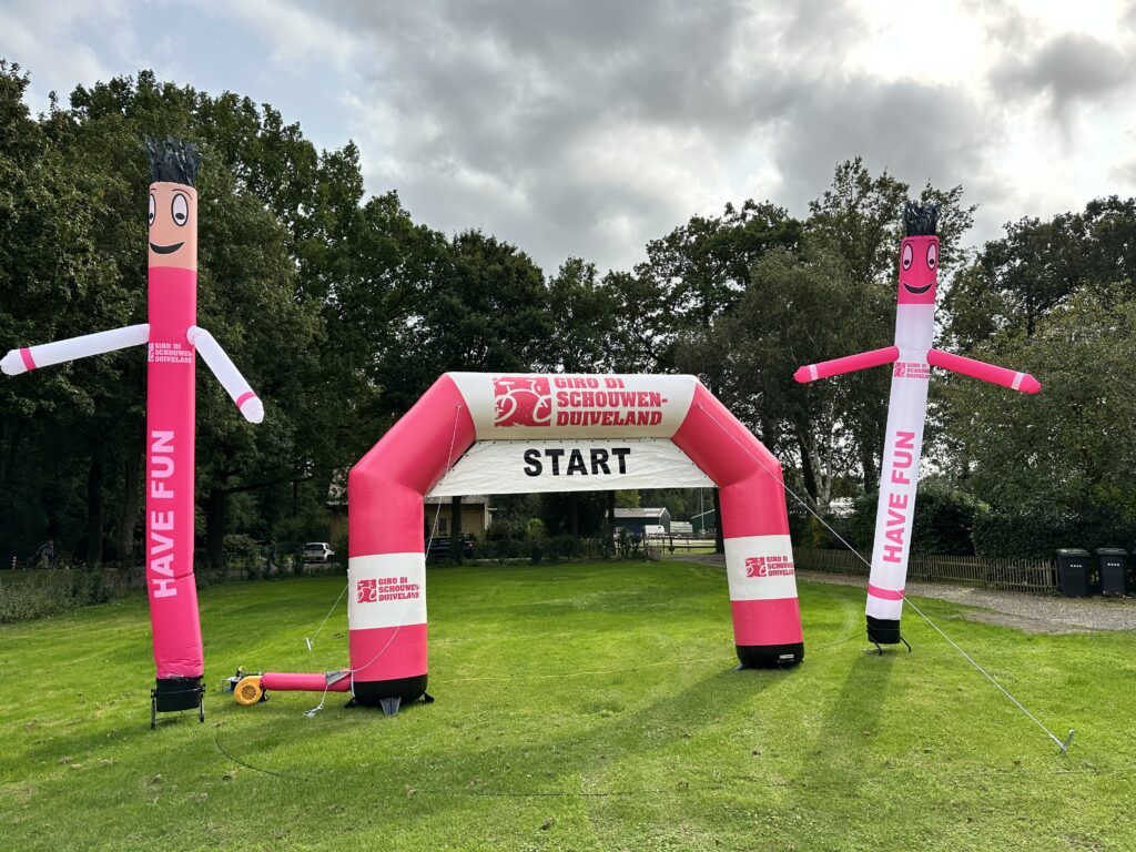 Roze opblaasbare startboog met twee skydancers bij een sportevenement