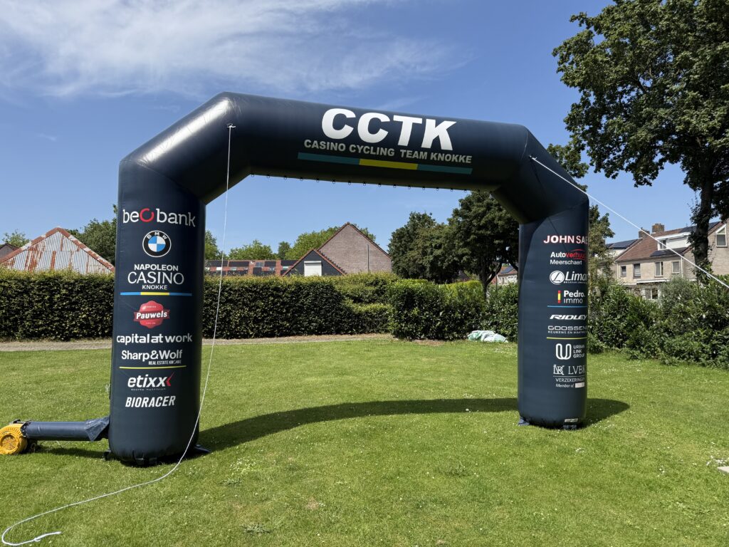 Zwarte opblaasbare finishboog met sponsorbedrukking op een grasveld