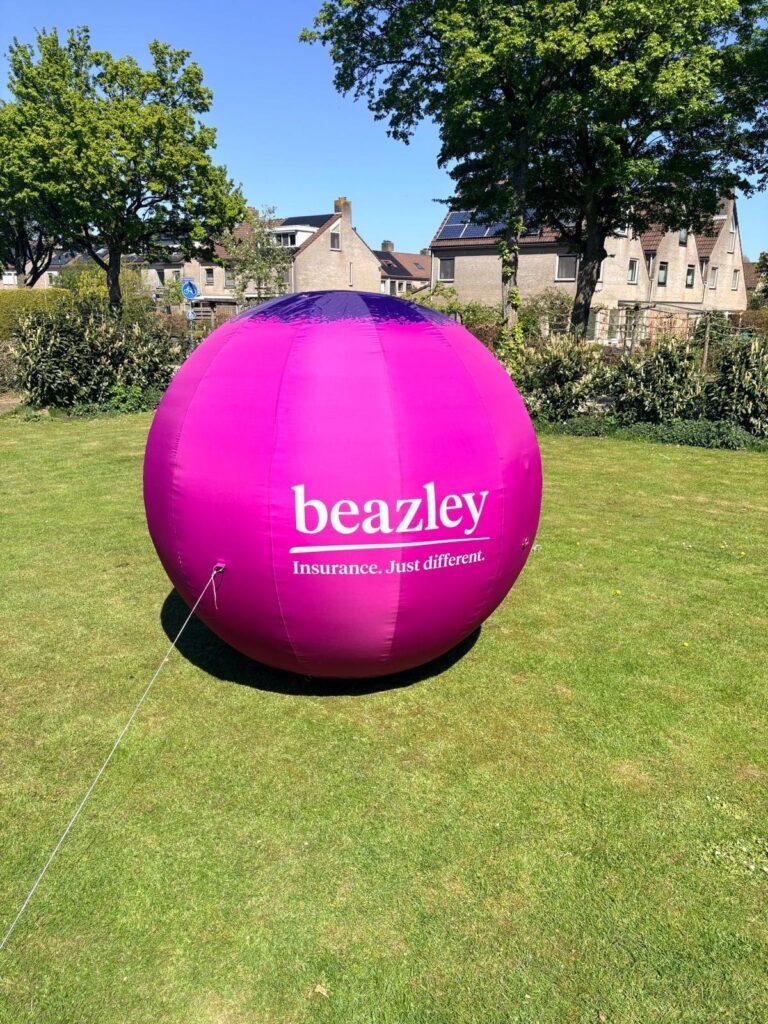 Roze opblaasbare reclameballon met bedrukking op een grasveld