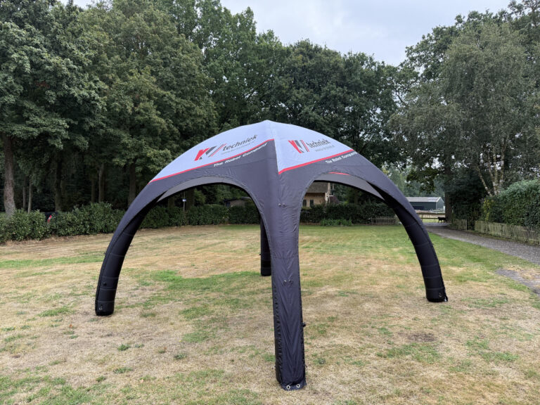Opblaasbare tent met open zijden en bedrukt dak op een grasveld
