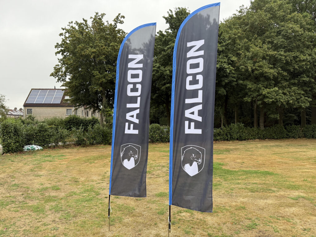 Twee beach flags met logo naast elkaar op een grasveld