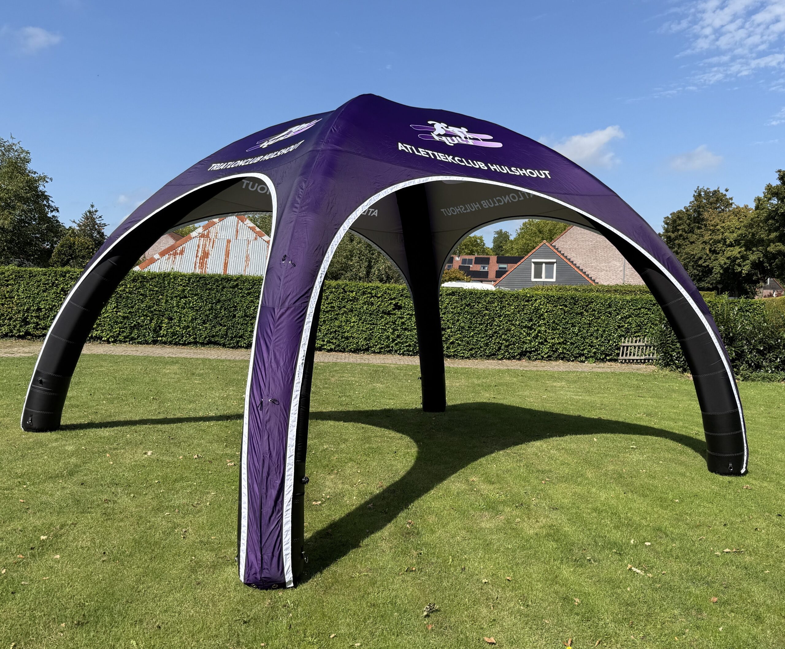 Paarse opblaasbare eventtent op een grasveld